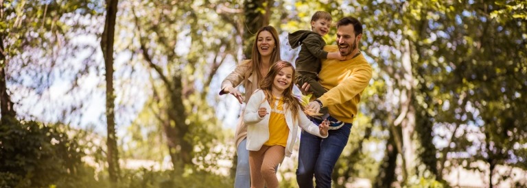 Een vader, moeder en 2 kinderen rennend door het bos