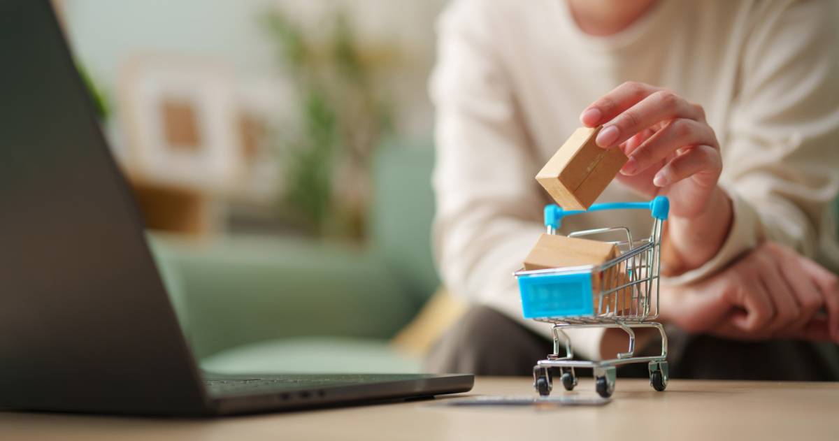 Vrouw voegt miniatuurverpakking toe aan winkelwagen naast de laptop