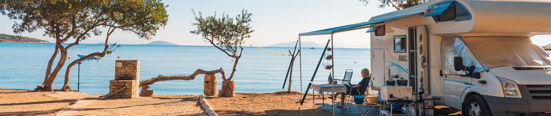 Familie die met een camper reist, eet ontbijt op een strand.