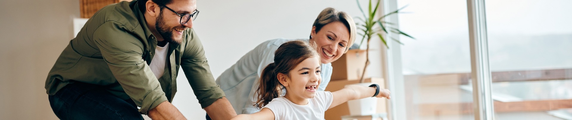 Gelukkige dochter die plezier heeft met haar ouders tijdens de verhuizing naar een nieuw huis